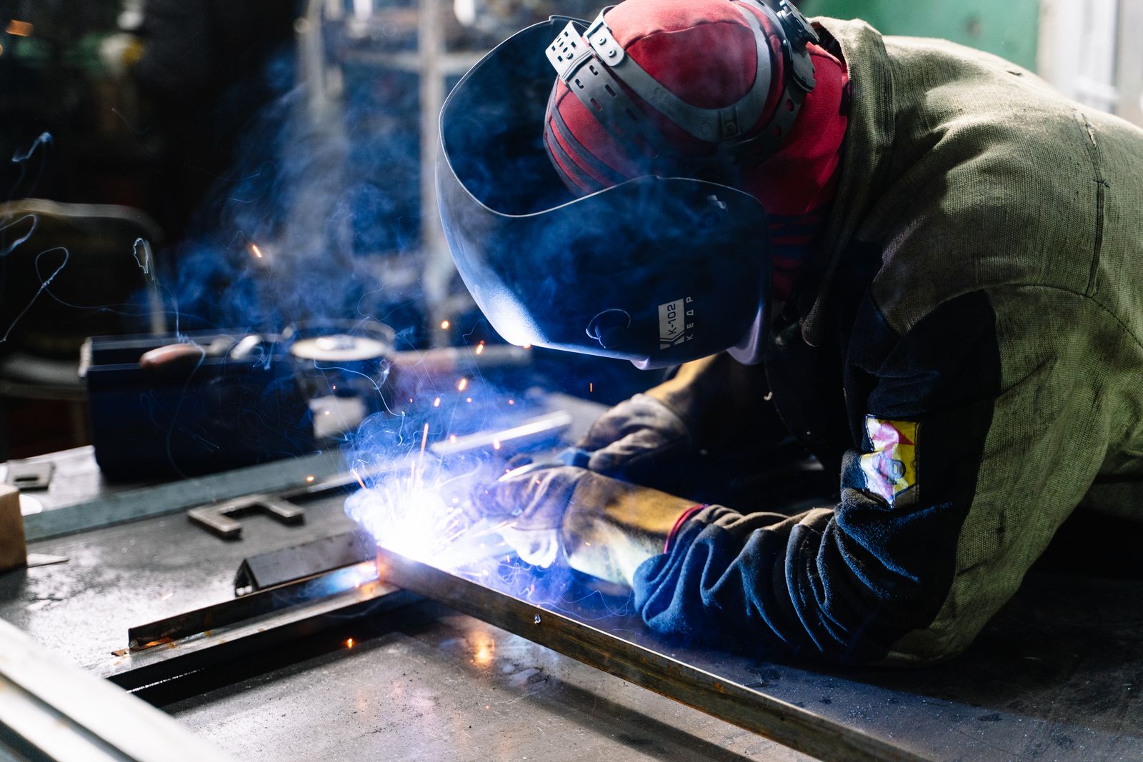 Lasser aan het werk met vonken in een werkplaats